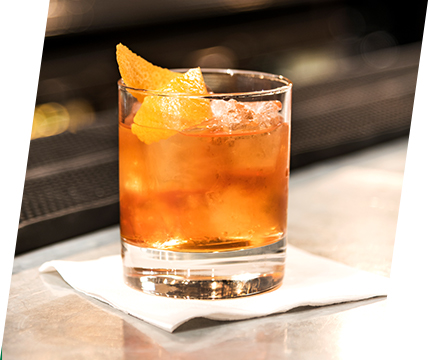 an old fashioned cocktail sits on a bar